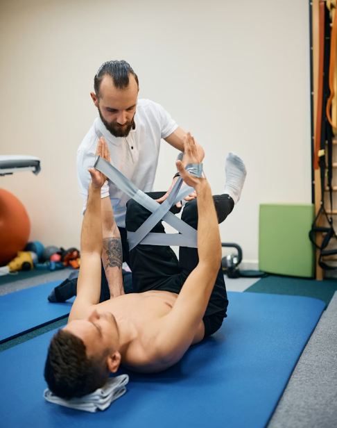 Fisioterapeuta deportivo asistiendo a paciente en ejercicio de rehabilitación con bandas elásticas