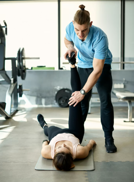 Profesional de fisioterapia deportiva asistiendo a paciente durante un estiramiento de pierna en sala de entrenamiento